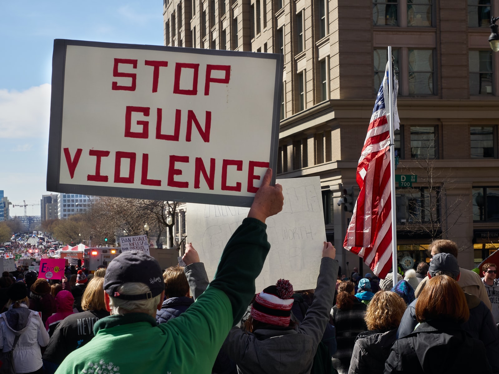 Man holding us stop gun violence sign in crowd of people