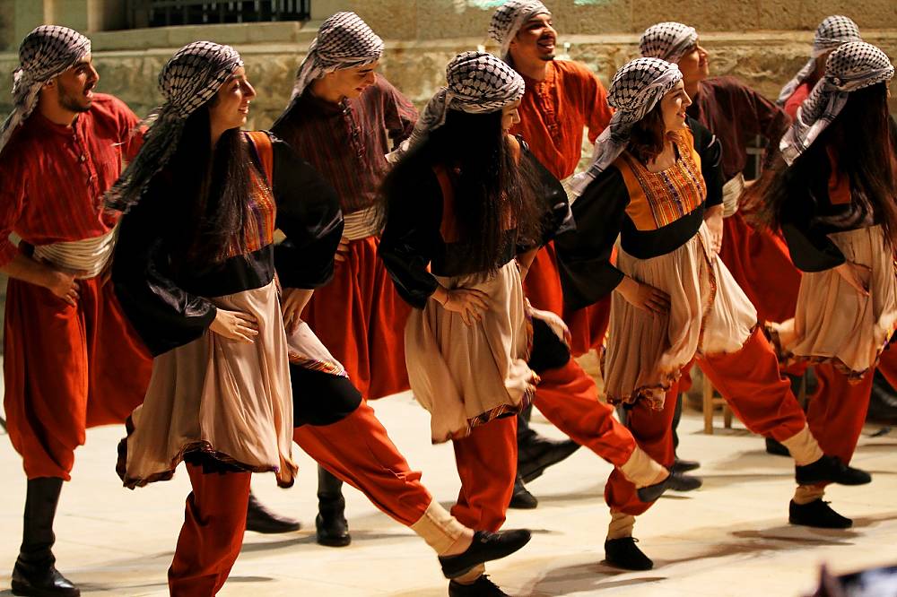 photo of ten Dabke dancers wearing traditional garb and keffiyehs on their heads