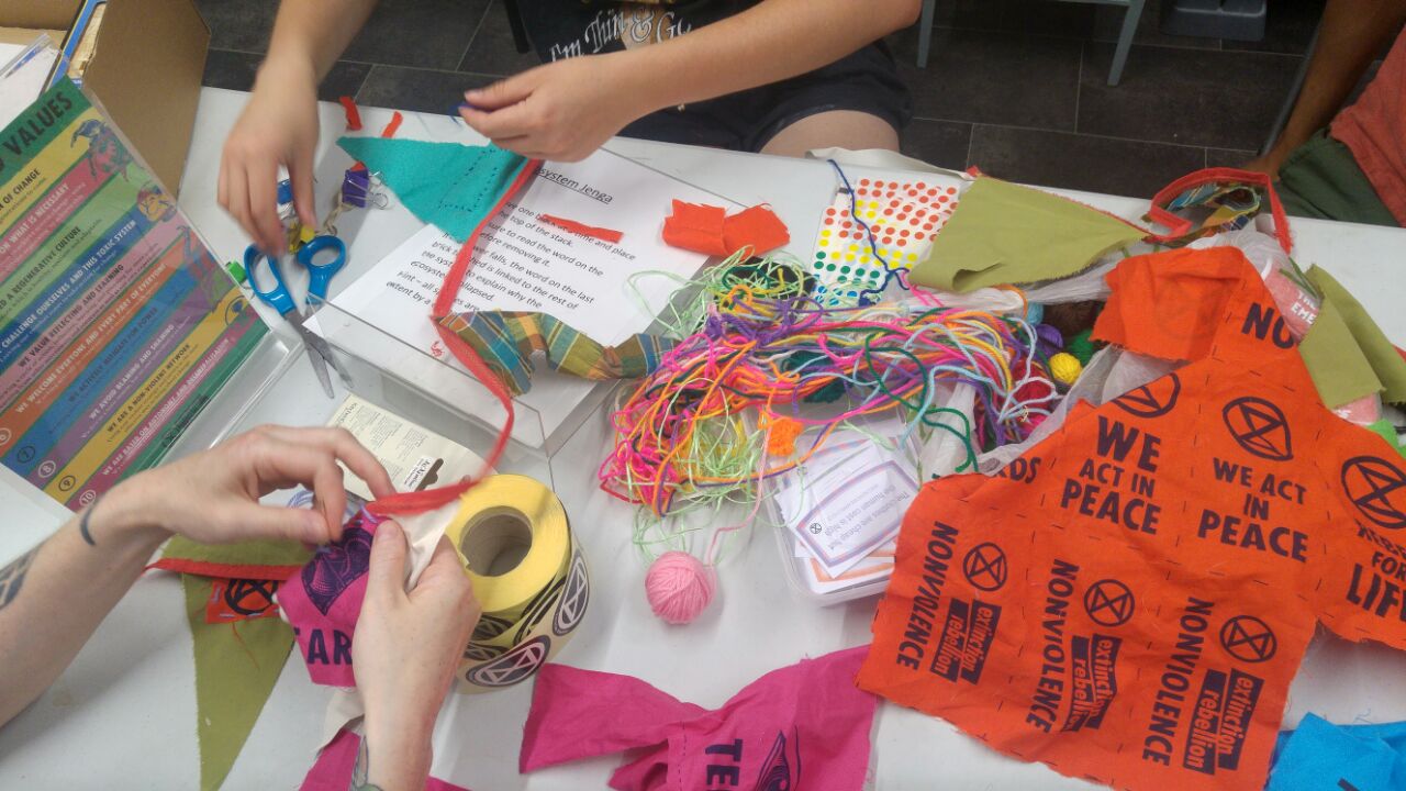 Patches, string and stickers on a table with hands working on the materials.