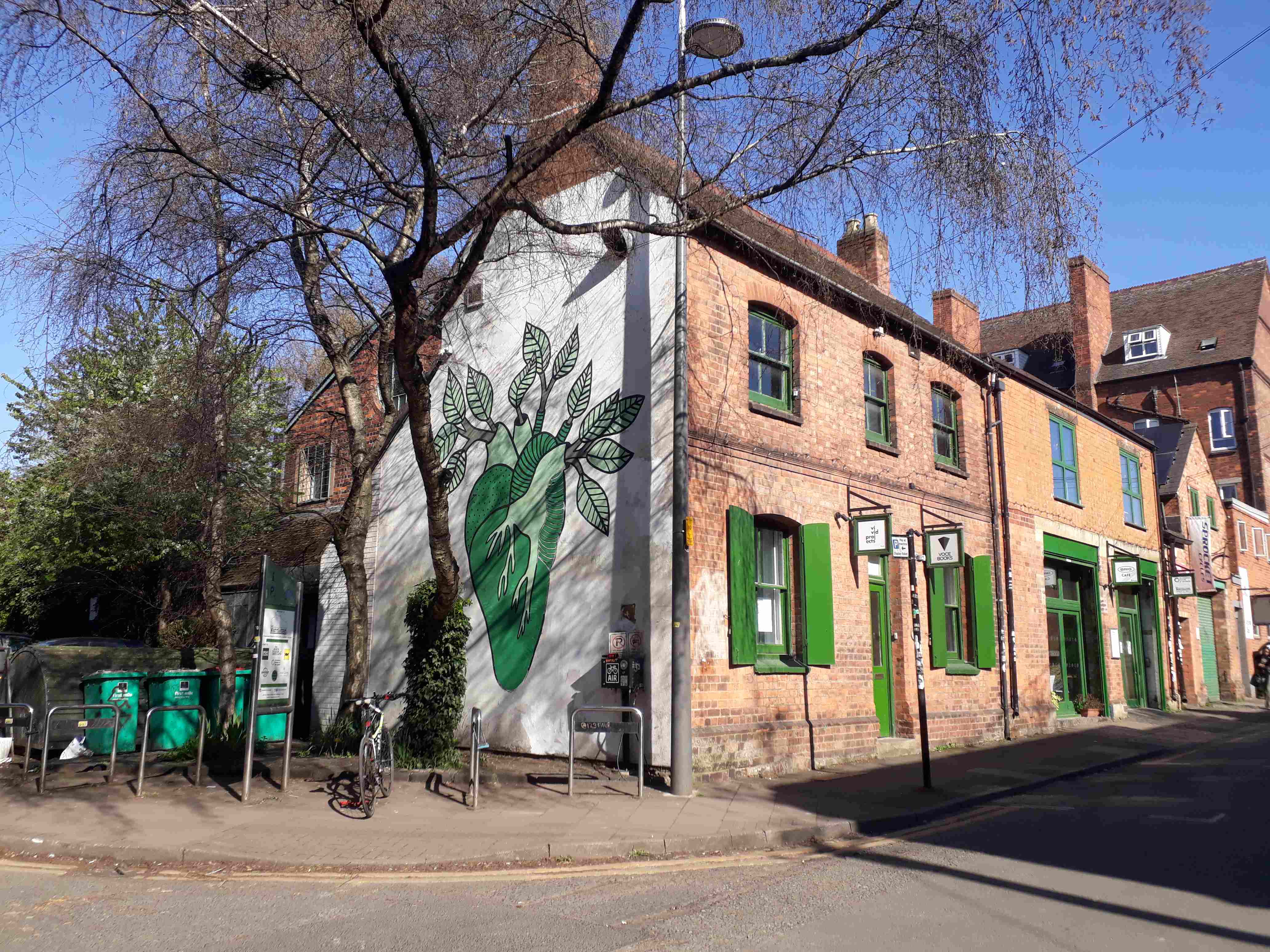 The Warehouse on a sunny day. A tree next to the building and bike stands.