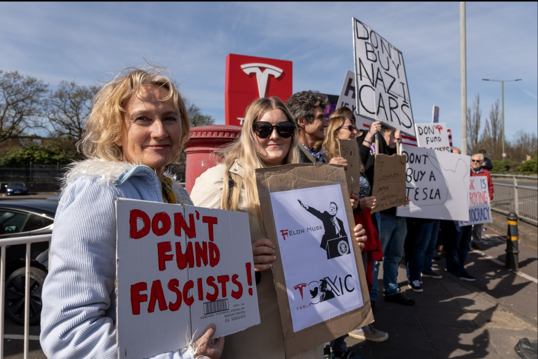 Group of people holding anti-Musk signs
