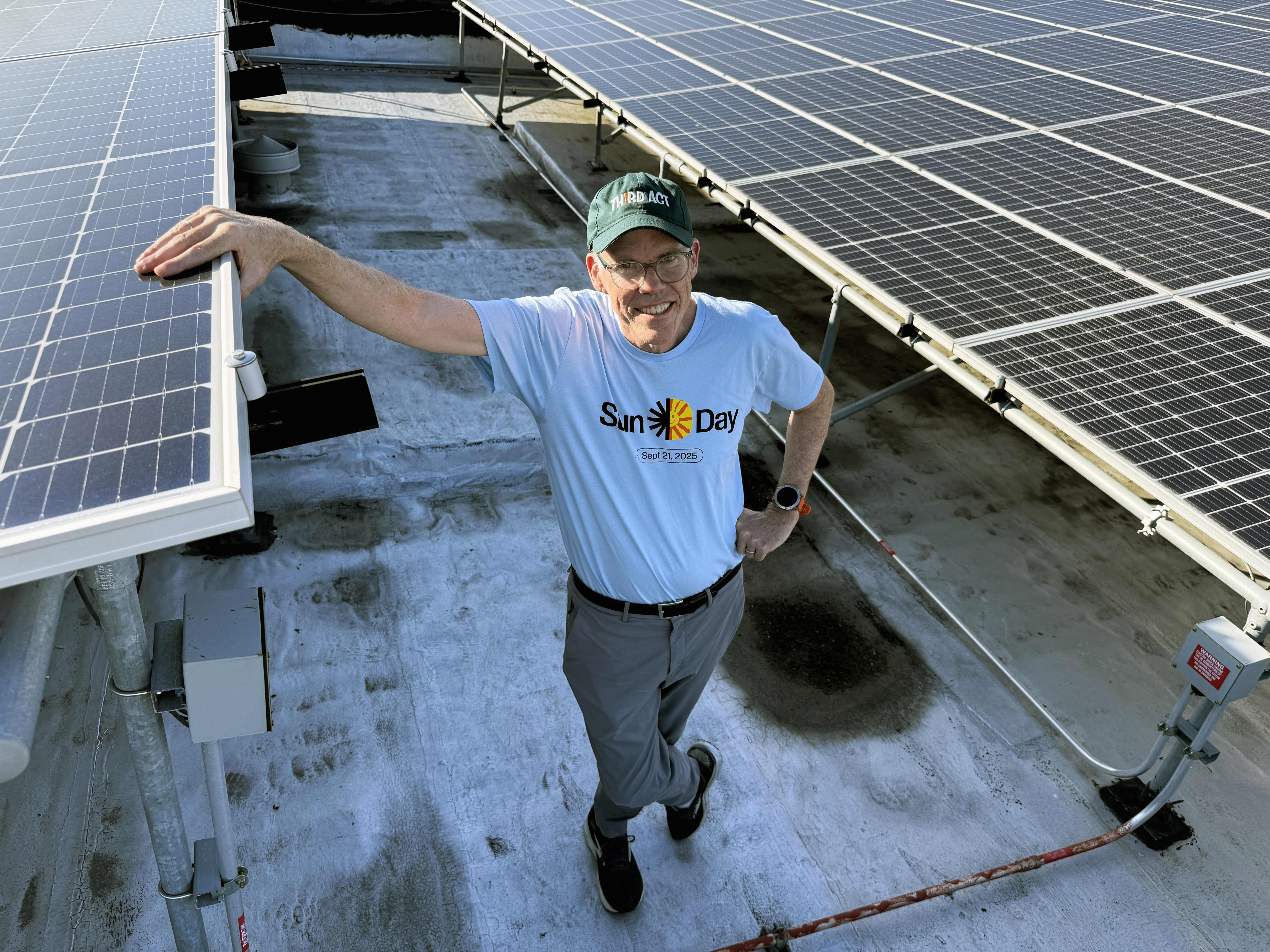 Bill McKibben standing and smiling in the middle of a solar array