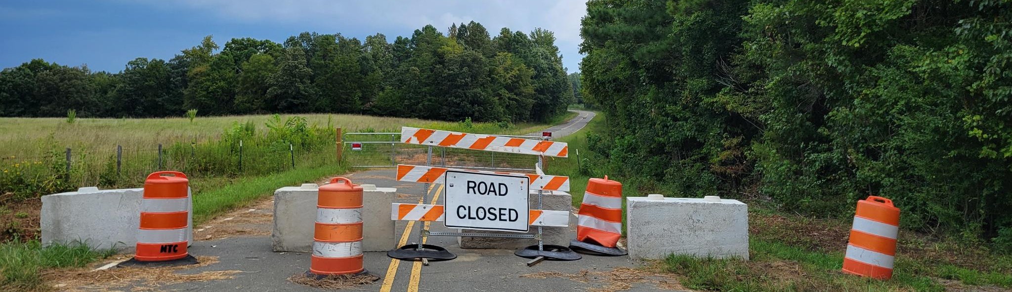 Country Club Road with a "Road Closed" sign and orange safety barrels closing off the road.