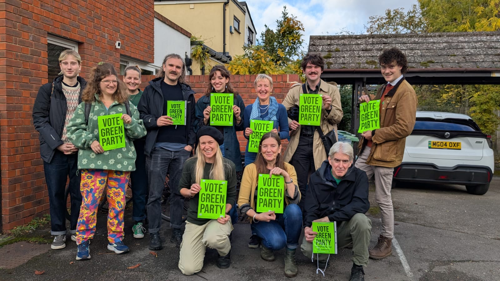 11 smiling people holding up "VOTE GREEN PARTY" signs
