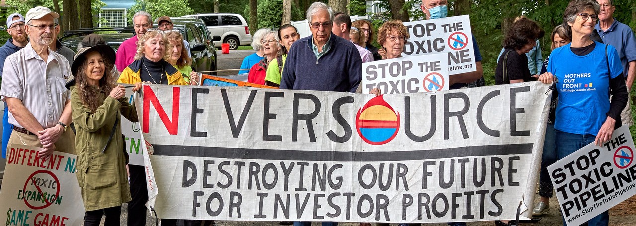 Rally-goers holding "Neversource" signs and a banner