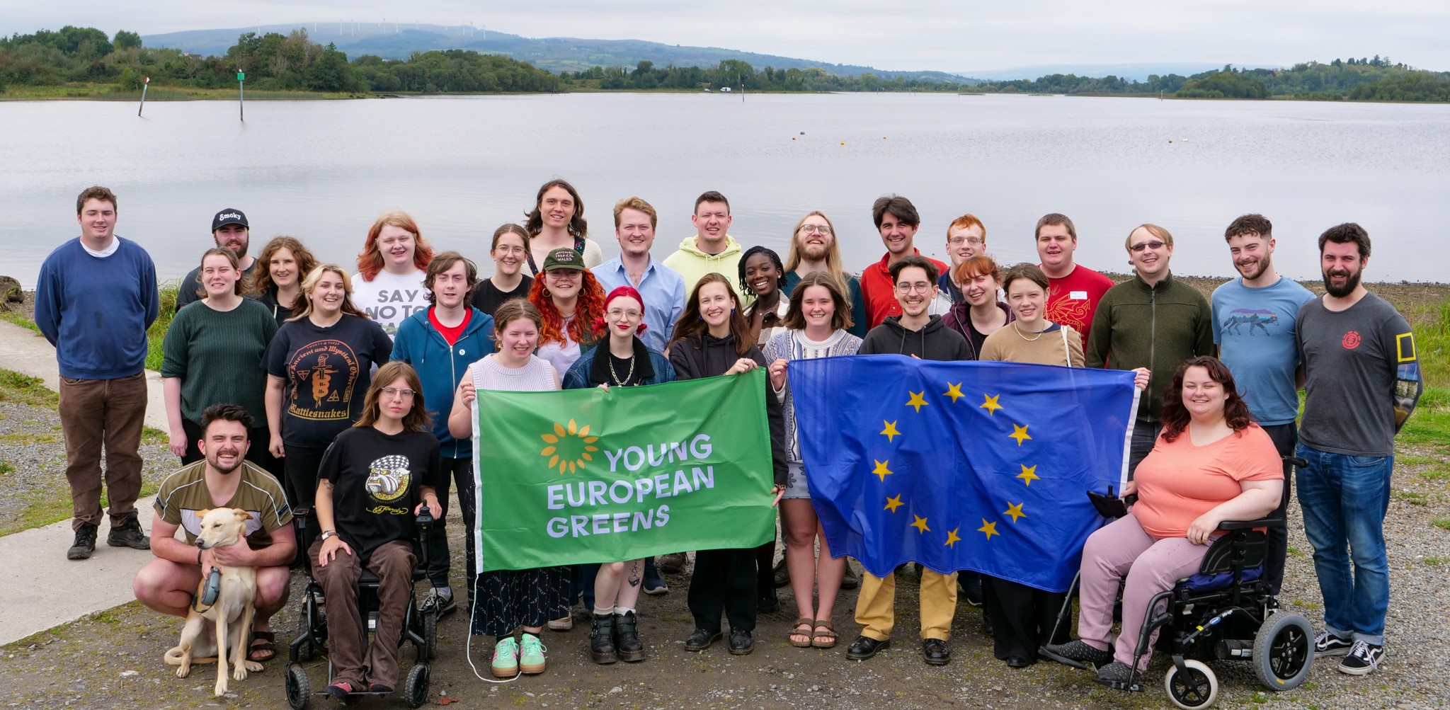 A group of roughly 30 Young Greens in front of a lough in Ireland holding an EU and a Young European Greens flag.