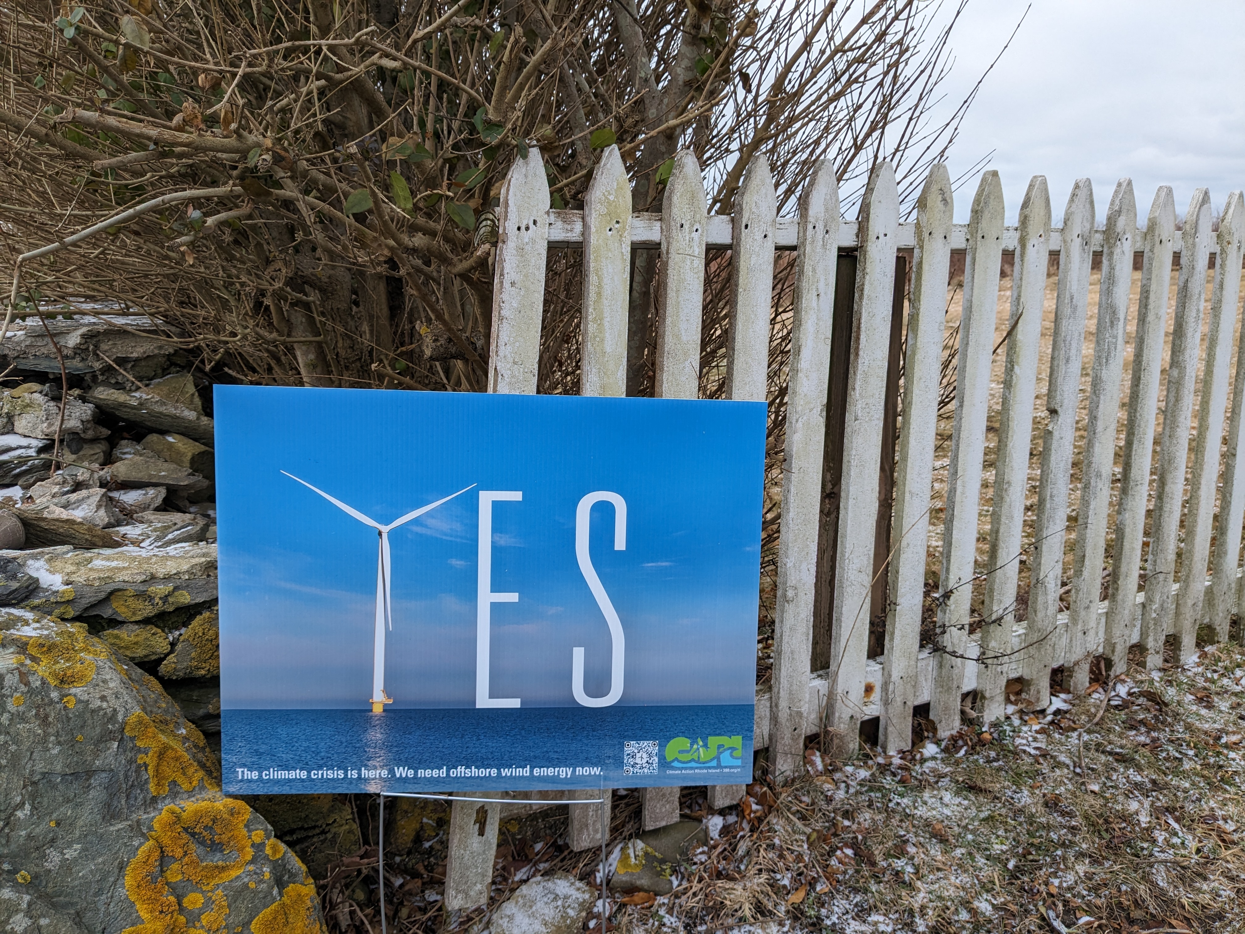 A yard sign that reads "YES" where the Y in the word yes is a wind turbine.