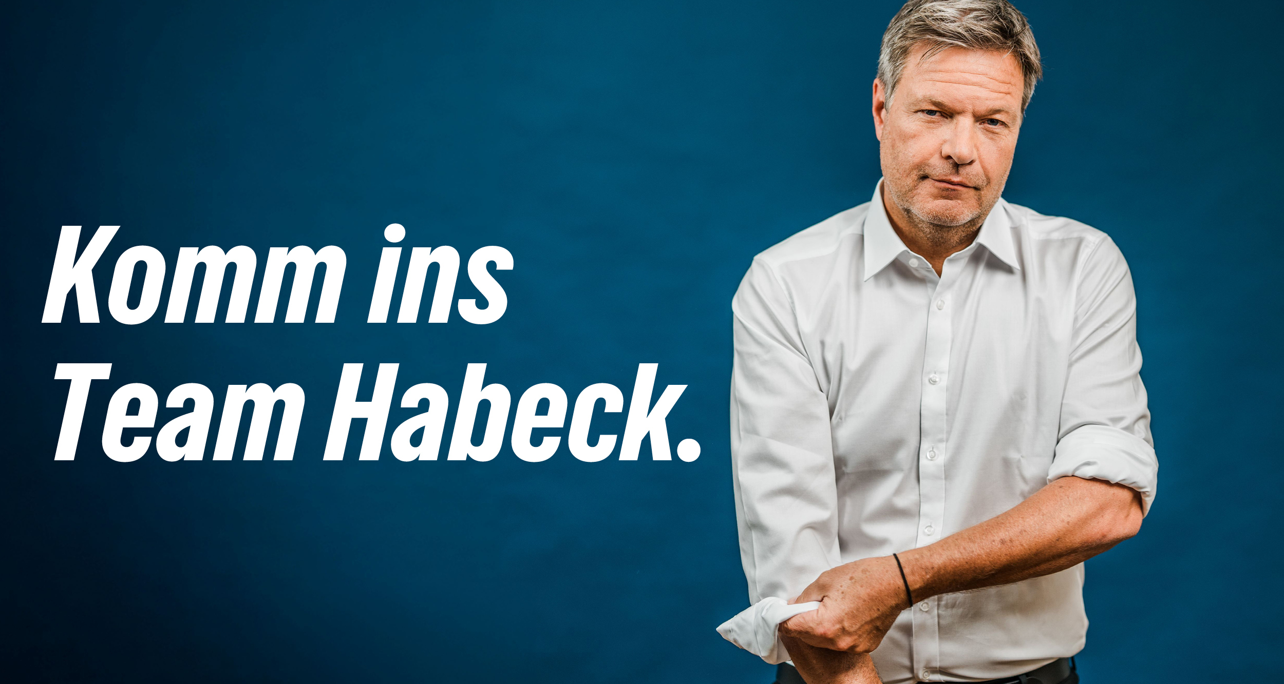 Robert Habeck steht vor einer blauen Wand. Er trägt ein weißes Hemd, welches er an den Ärmeln hochkrempelt. Links steht groß: Komm ins Team Robert.