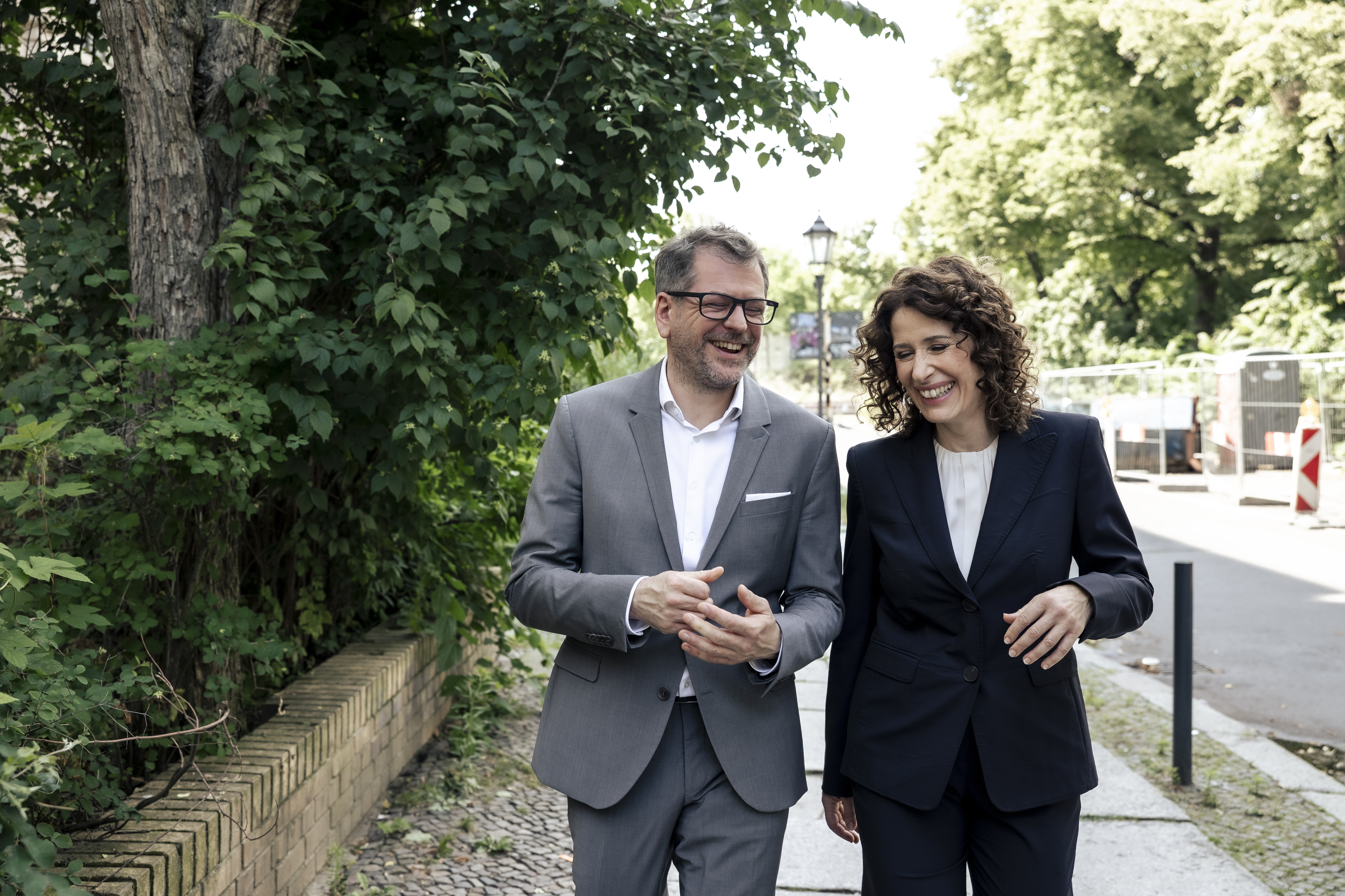 Werner Graf und Bettina Jarasch gehen nebeneinander die Straße entlang.