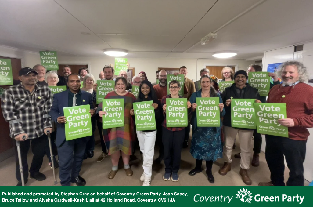 Image shows a group of people standing holding "Vote Green Party" posters.