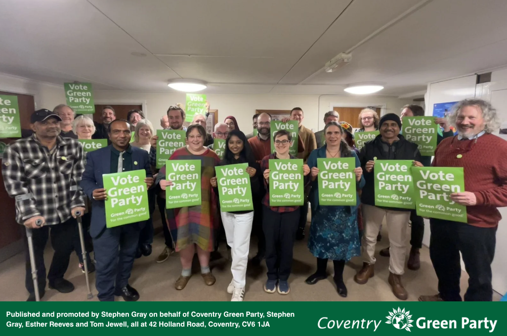 Image shows a group of people standing holding "Vote Green Party" posters.