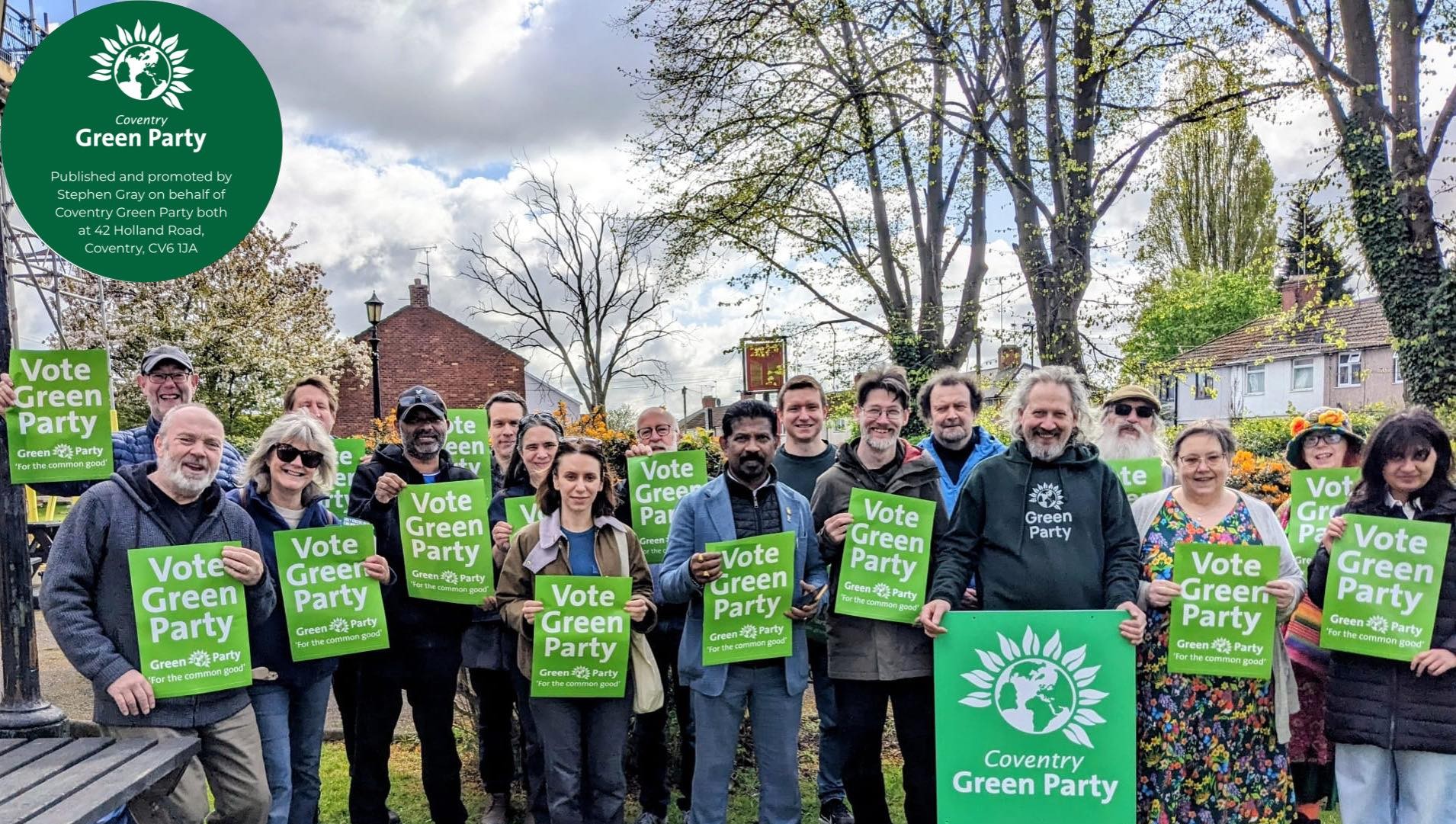 Image shows a group of people standing holding "Vote Green Party" posters
