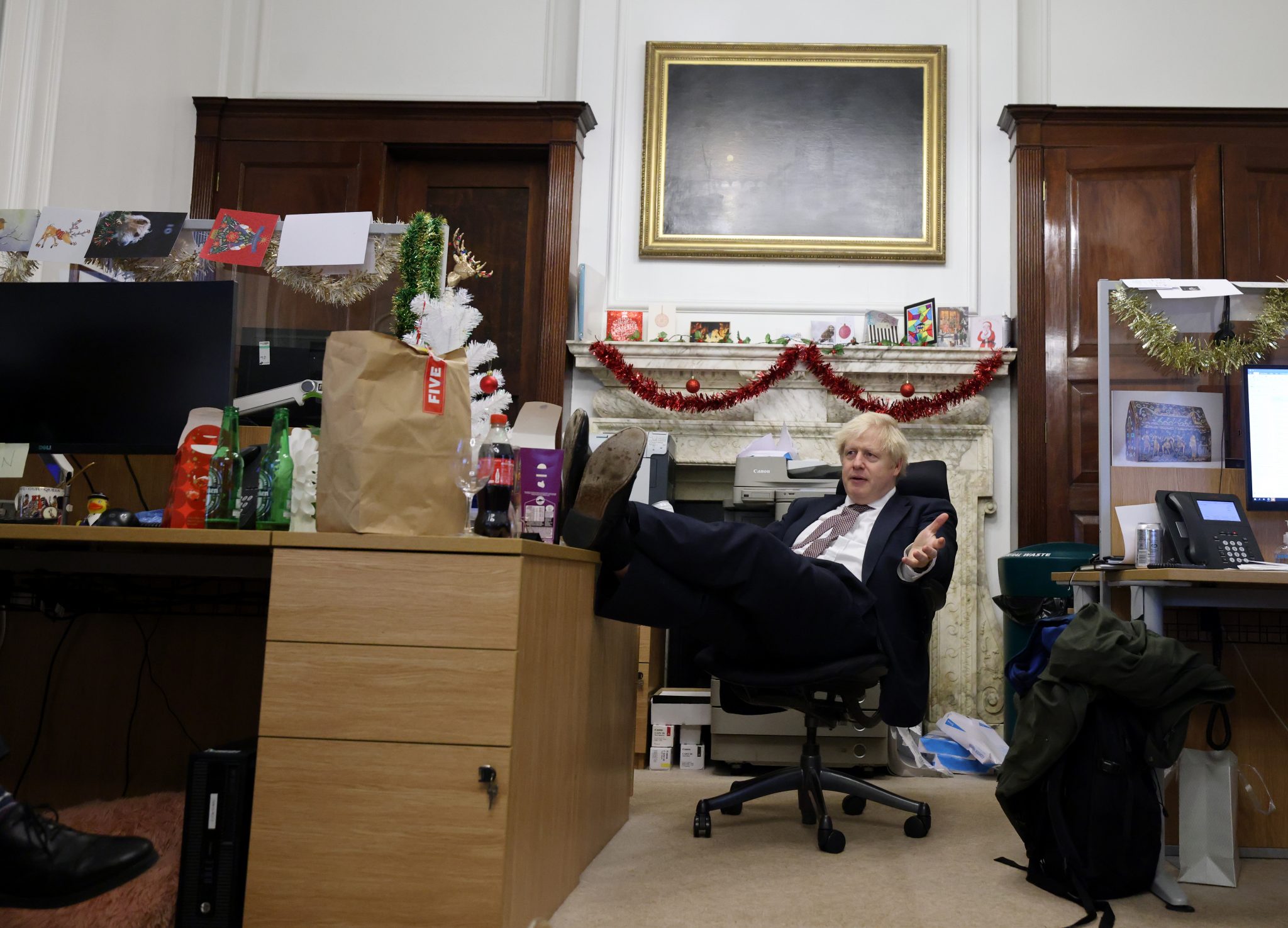 A picture of Boris Johnson sitting in a chair in Downing Street, feet up on a desk, sometime during a Christmas in the middle of the early pandemic