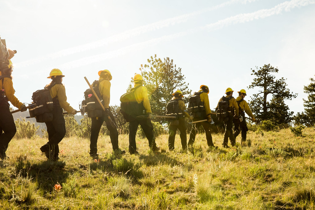 Line of service members with tools and hard hats walking into the sun