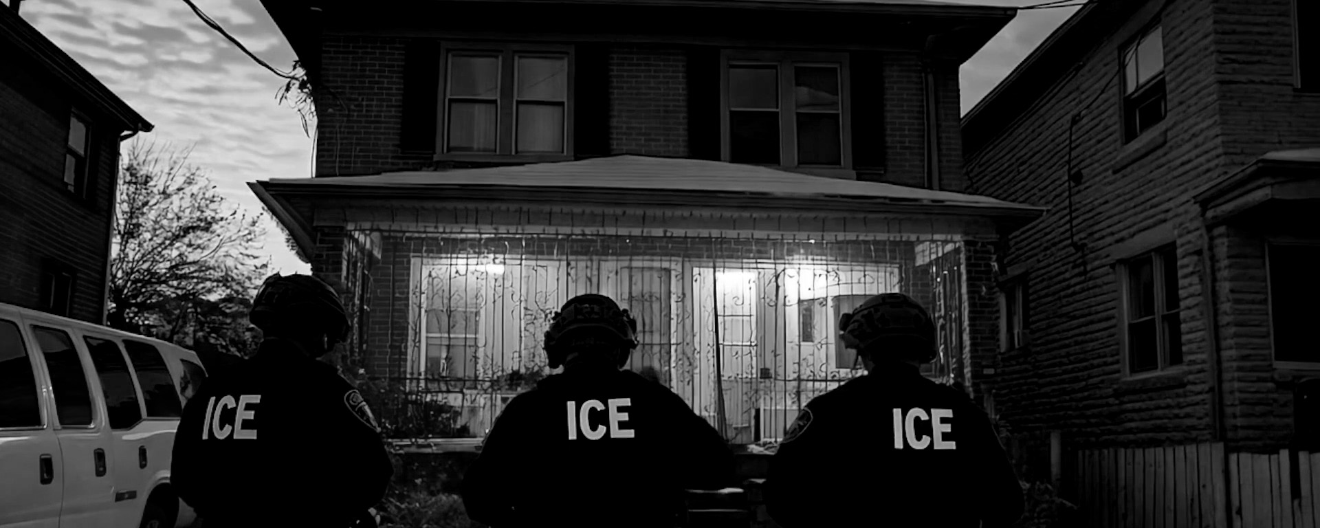 Three American Gestapo (ICE) agents outside a home.
