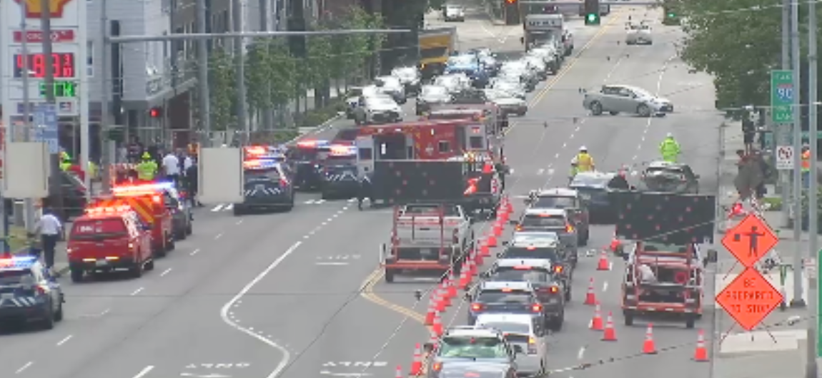 A view of Rainier Ave S showing six lanes of traffic, construction closures, and flashing lights.