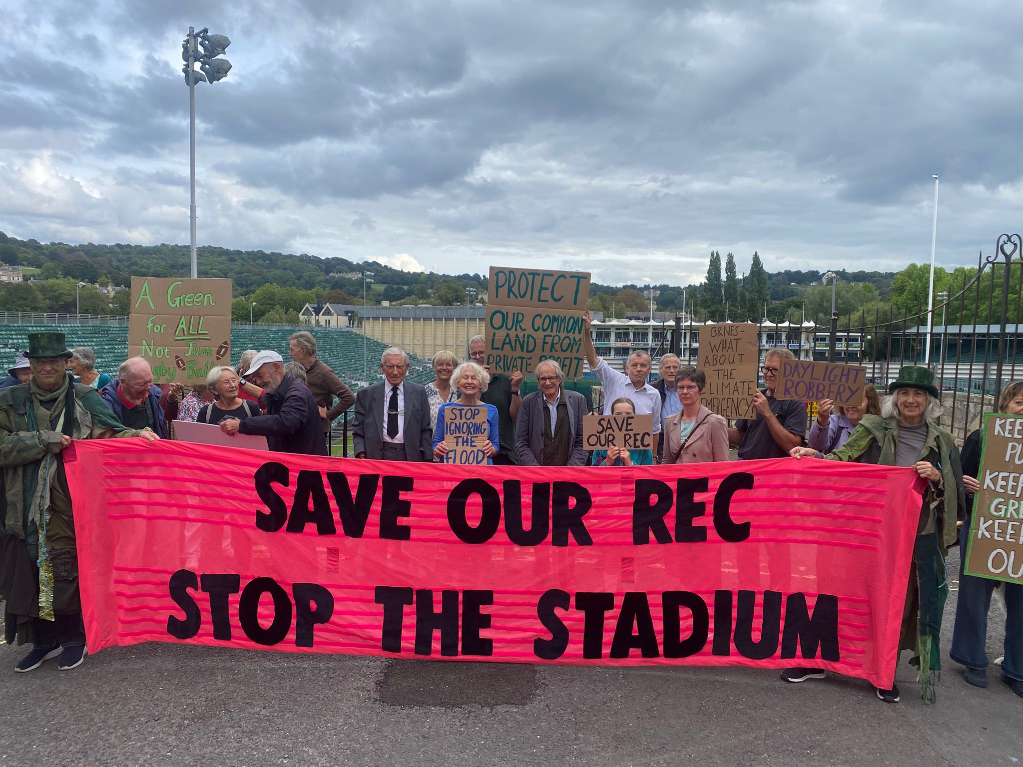 group of people holding up a sign saying Save Our Rec Stop the Stadium, in front of the Bath Rec