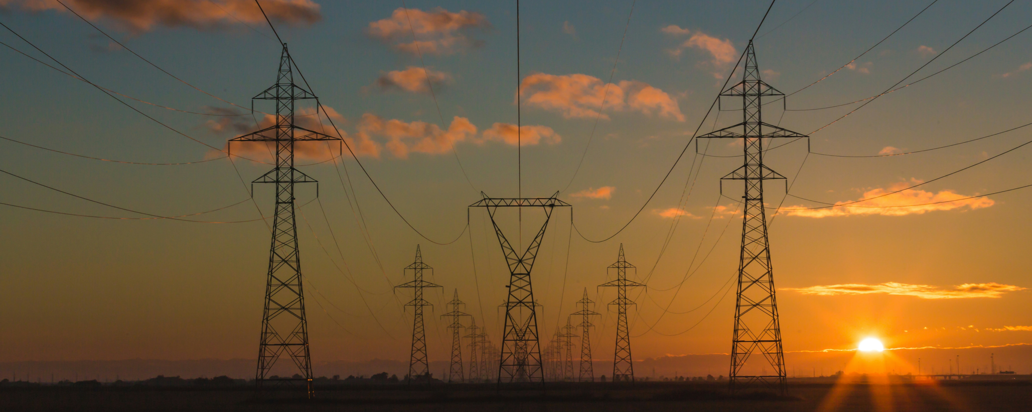 Electric transmission lines with the sun low on the horizon