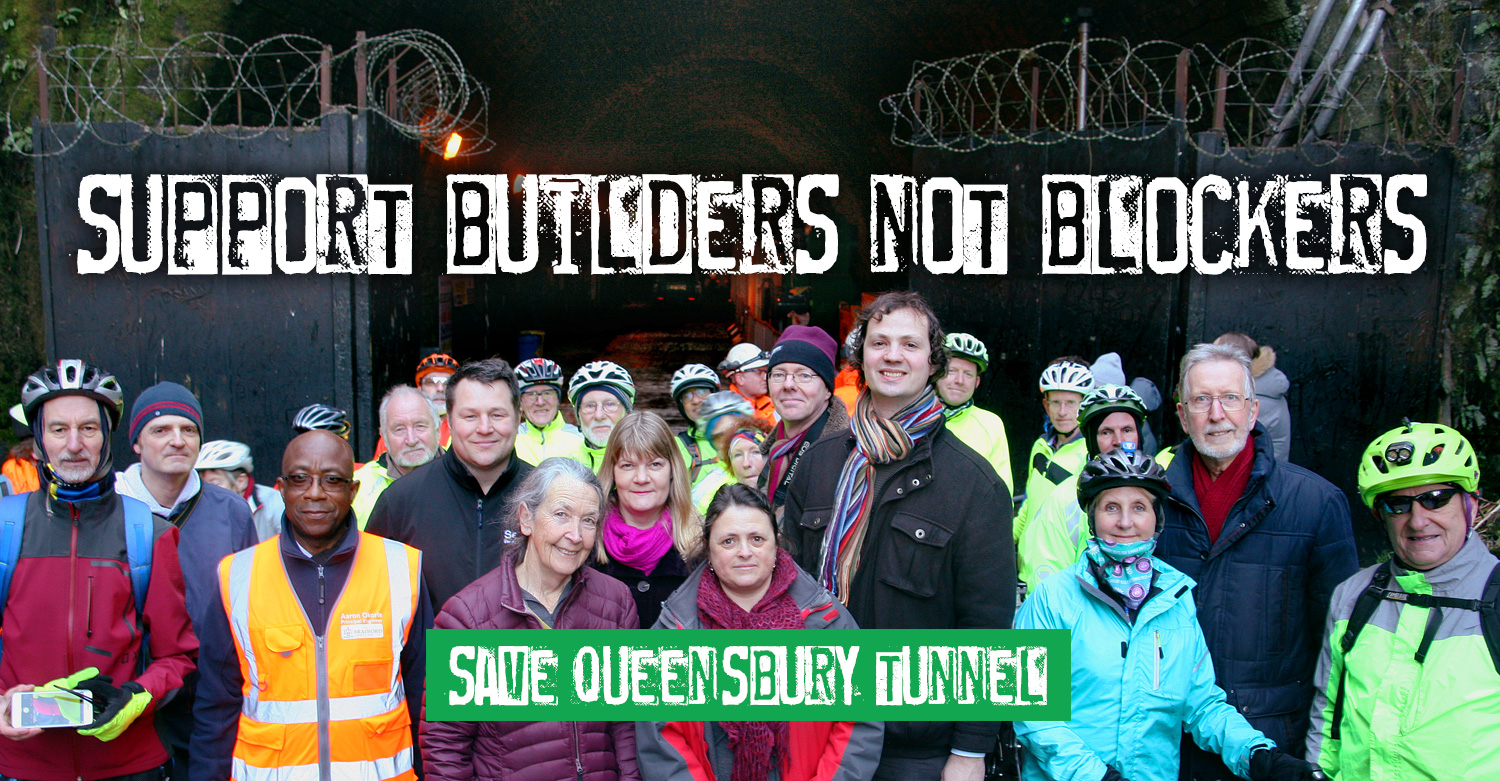 Local people outside one of the Queensbury Tunnel entrances with wording across the top saying 'Support builders not blockers' with a banner image across the bottom of the photo saying 'Save Queensbury Tunnel'