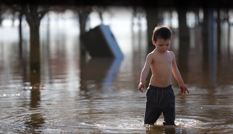 boy wading through floodwaters (Big Bambi Productions/Shutterstock)