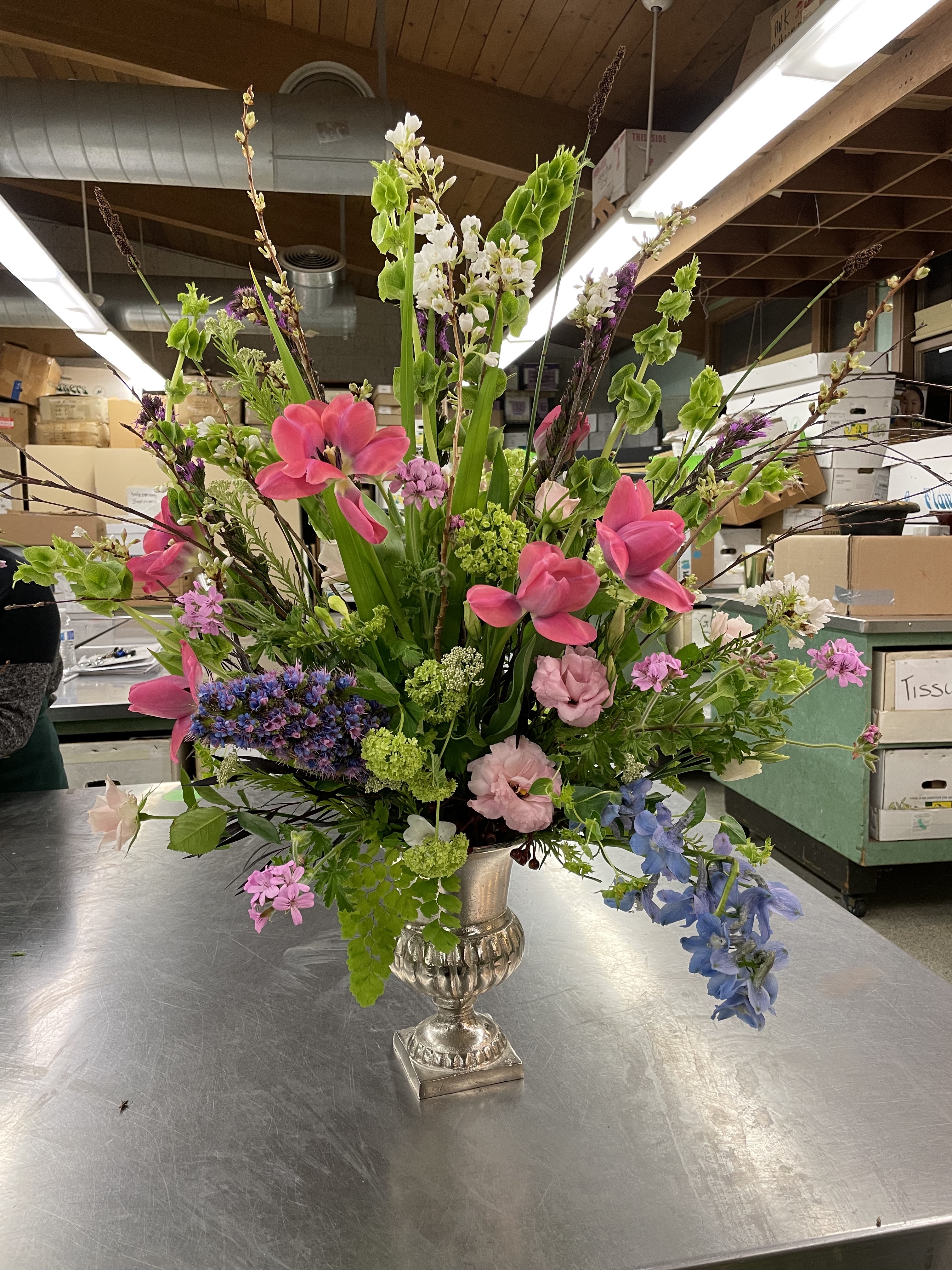 Lush Flemish style fan arrangement with bright pink tulips, geraniums, and lisianthus.