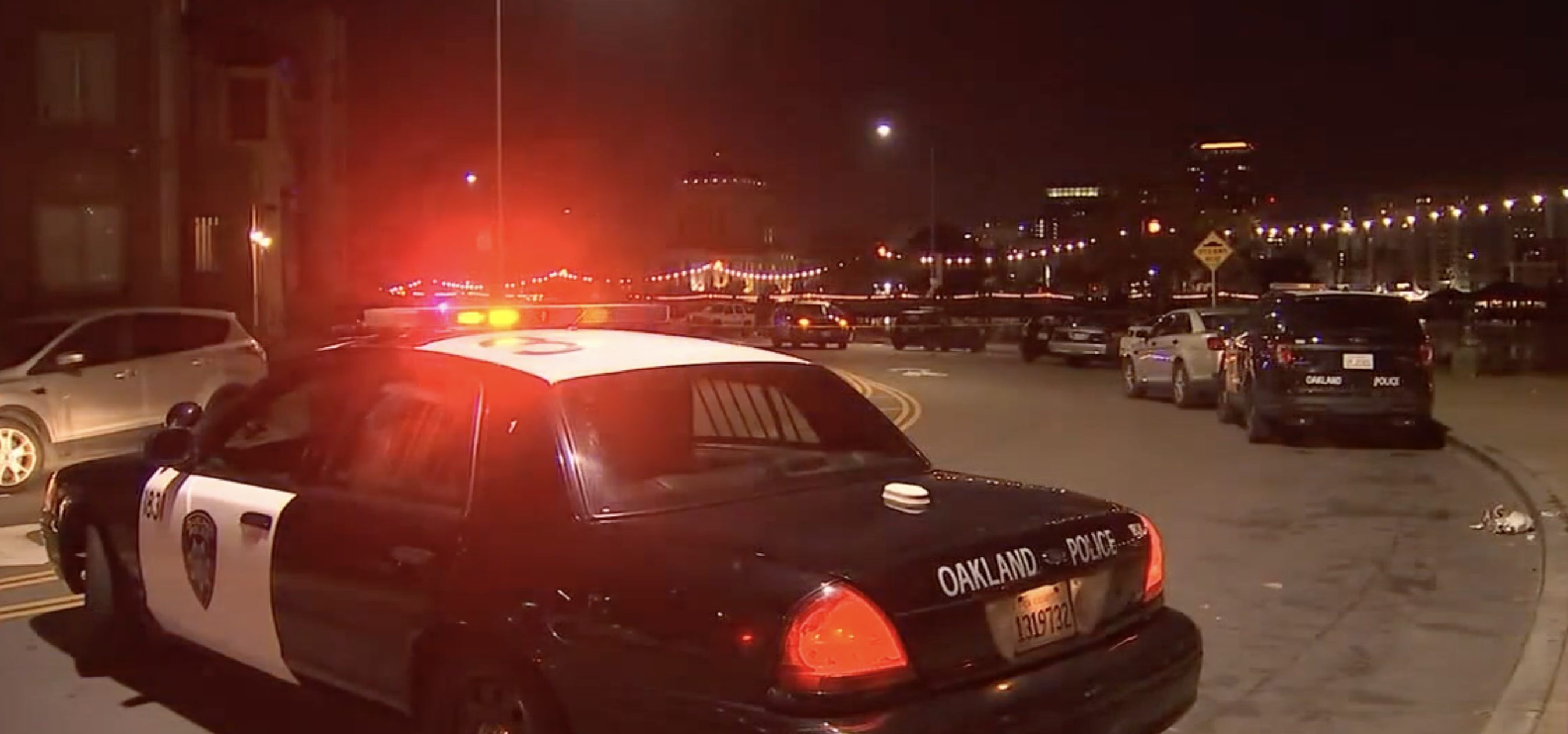 Police car in the street after a murder. Cars parked on the street. Night time.