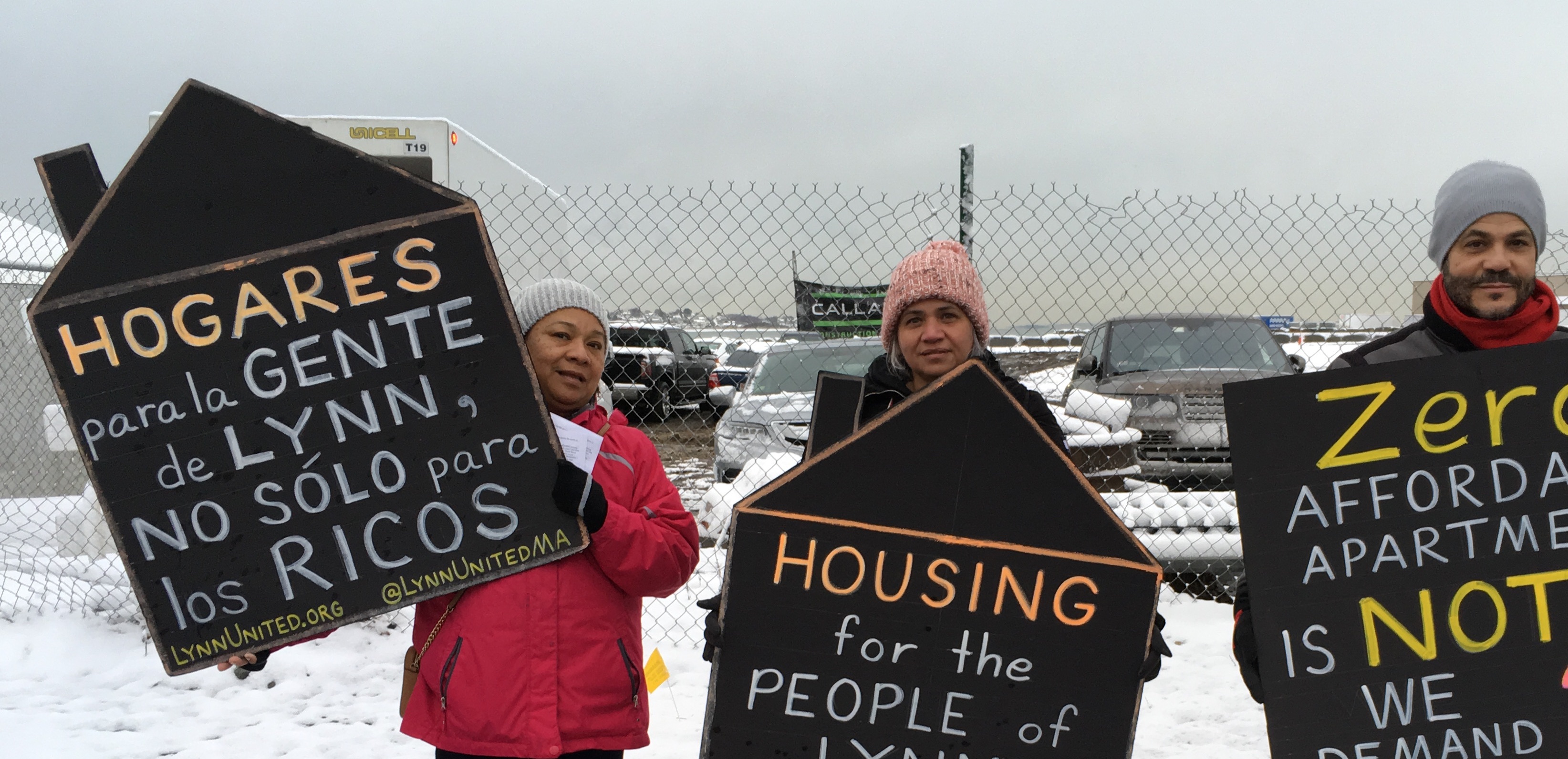 Fotografía de personas con letreros de protesta. Un letrero destacado dice: "Vivienda para la gente de Lynn, no solo para los ricos"