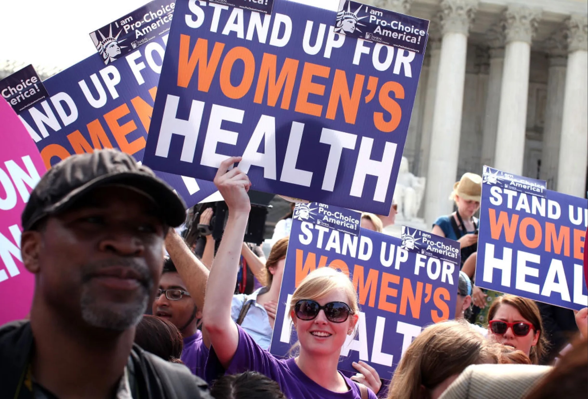 An image from a protest in Washington DC with many people holding signs that say "stand up for women's health."