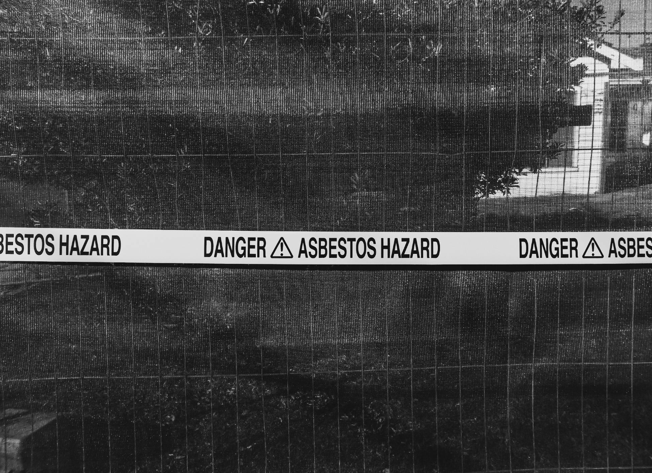 Photo of a home blocked off with a warning sign reading "Danger Asbestos Hazard"