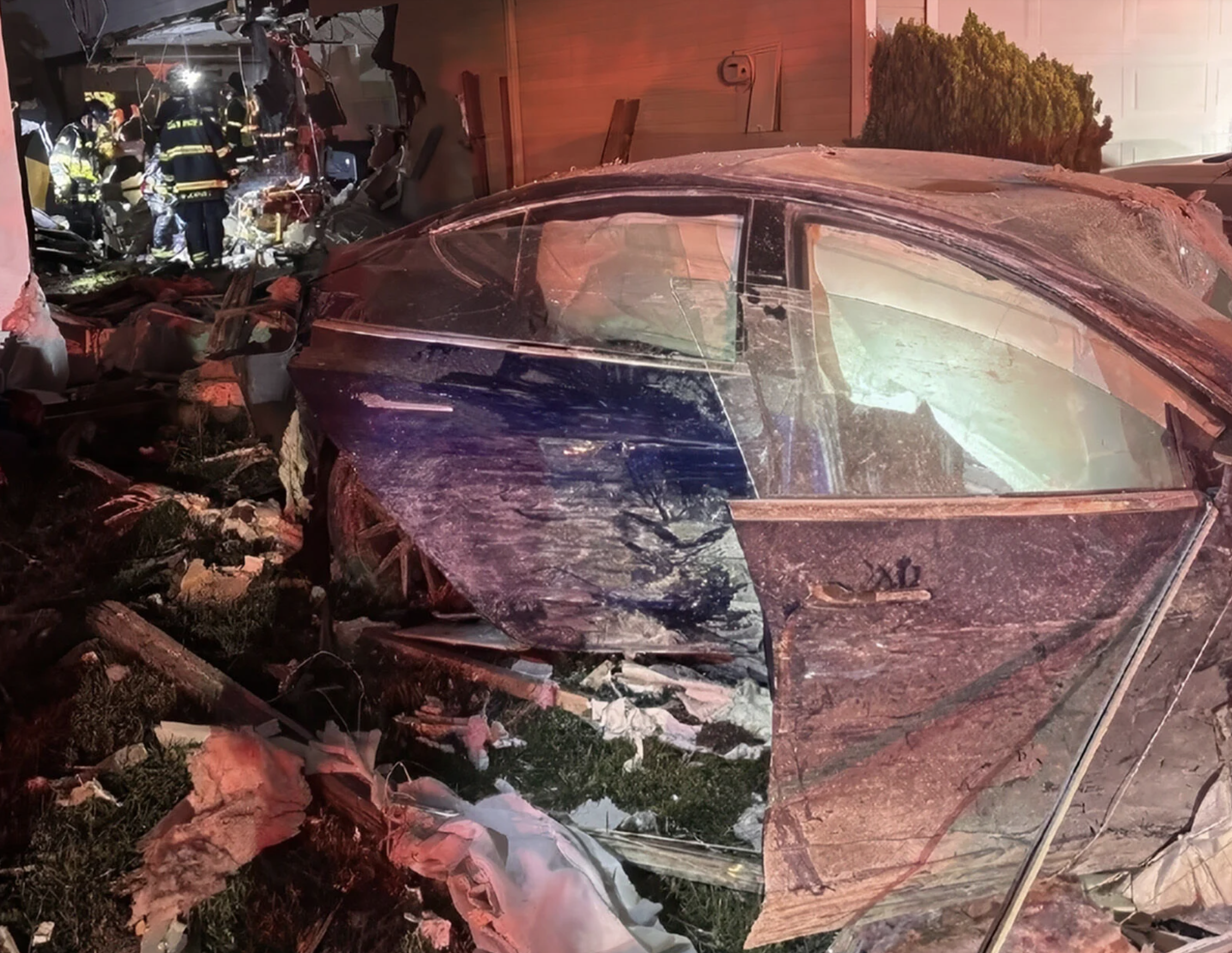 A Tesla sedan sits damaged at a residence on the 300 block of Thatcher Lane in Foster City Sunday. The 29-year-old female driver allegedly traveled at a high rate of speed before crashing through a backyard fence and through the side of the home and coming to rest after colliding with a light pole in the front yard. 