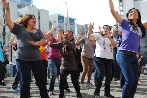 Image of Latina women in the streets with hands in the air dancing