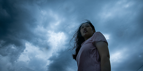 A woman standing in front of a stormy sky