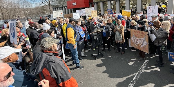 A crowd gathers to protest in front of a Social Security office.
