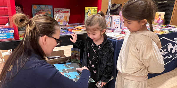 Teacher showing two young girls a book