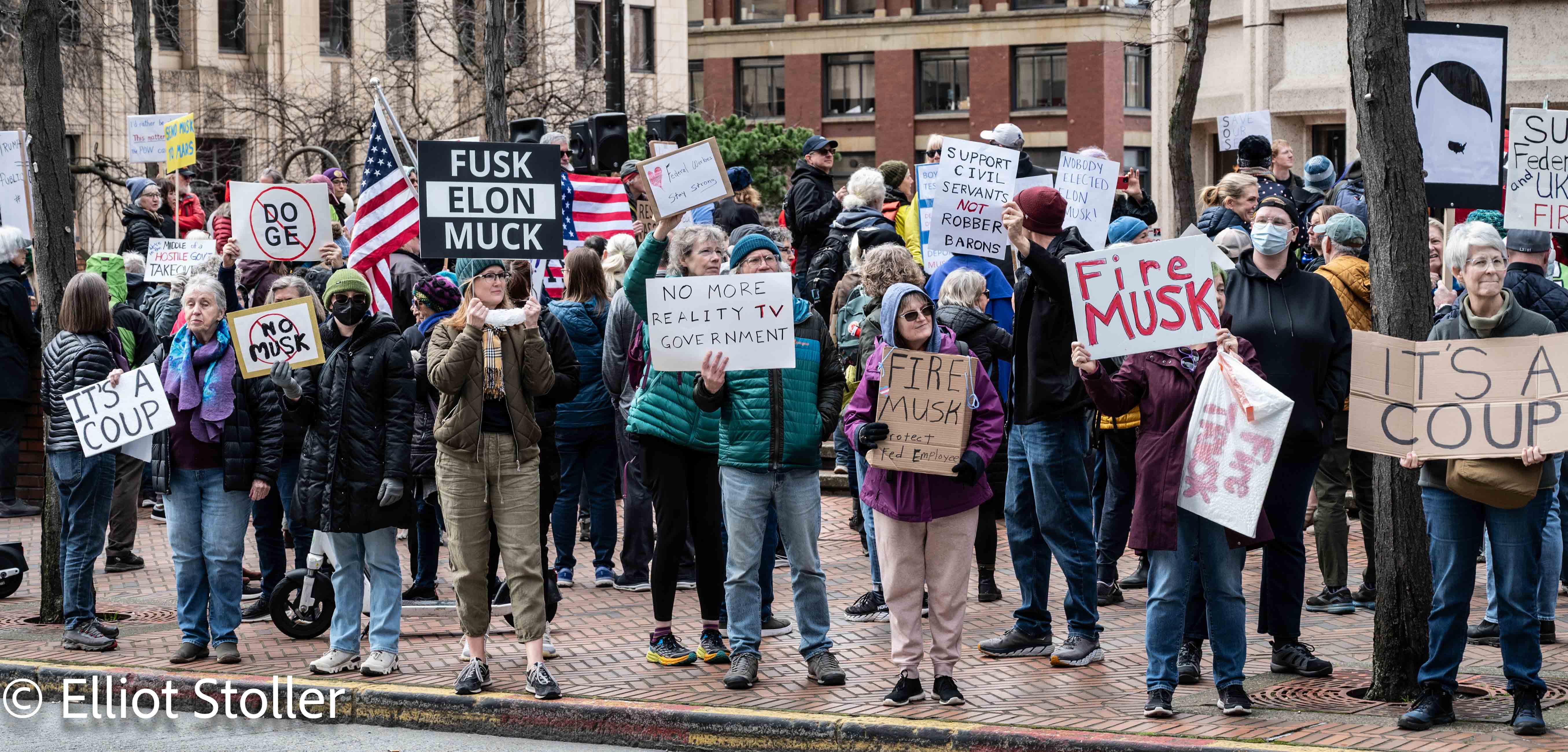 The photo shows a crowd of people protesting outside the Henry M. Jackson Federal Building. 
