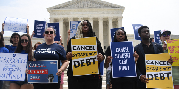 Young people in front of the Supreme Court building with signs that say "Cancel Student Debt"