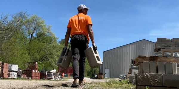 Student carrying cinder blocks, walking away from the camera