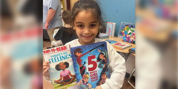 Young girl smiling and holding books
