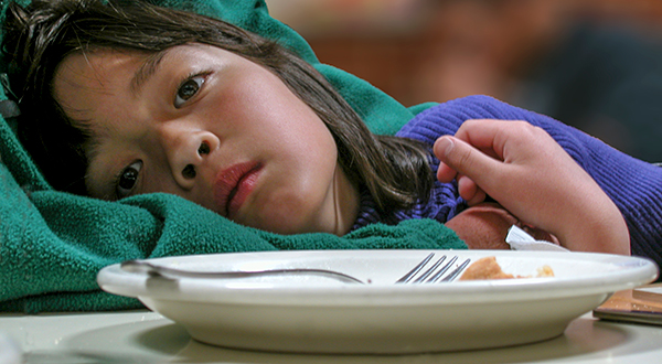 Young girl looking tired in front of an empty plate