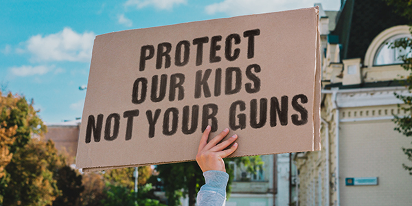 Protest sign says "Protect Our Kids, Not Your Guns."