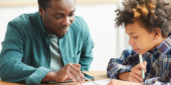 Black male teacher helping young boy with schoolwork