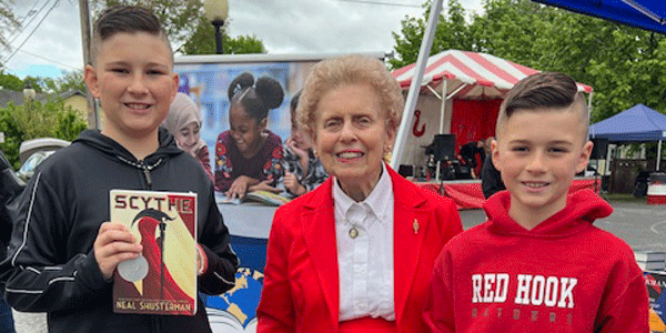 An older woman smiling, flanked by two young students