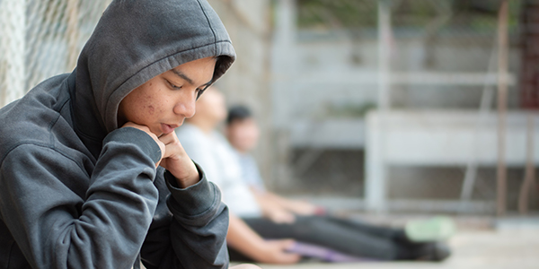 Contemplative teen wearing a hoodie, looking down