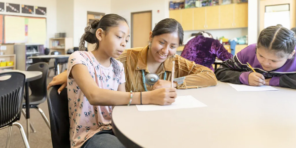 A Native American student and Native American teacher working together in a school room