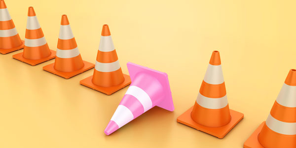Orange caution cones lined up, with one pink one toppled over
