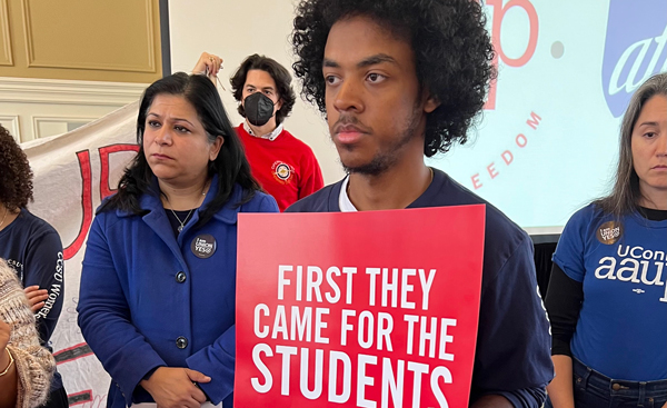 A student and unionists standing with a sign that says "First they came for the students"