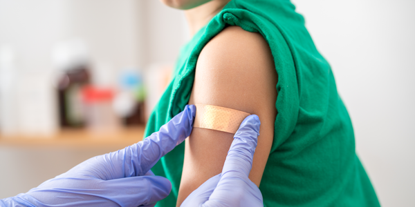 a child's arm with someone placing a bandage on it
