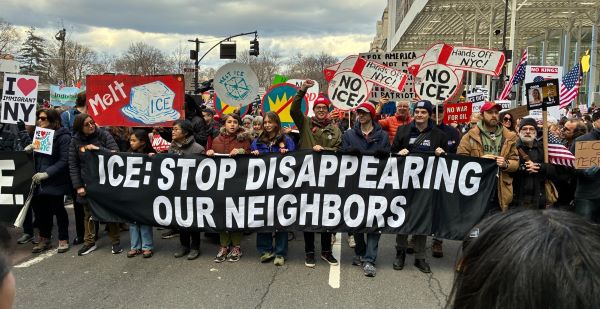 A crowd of protesters with a sign, "ICE: Stop Disappearing Our Neighbors"