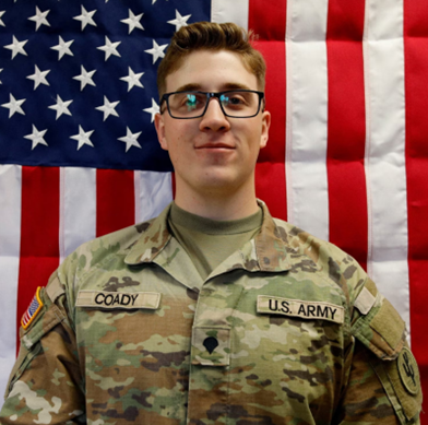 U.S. Army Reserve Sgt. Declan Coady of West Des Moines in his uniform in front of an American flag.