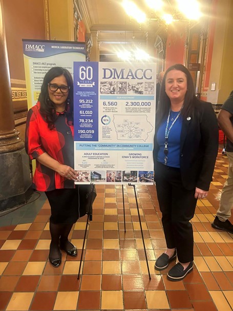 Senator Hardman and a staff member of DMACC stand beside a DMACC sign in the Capitol Rotunda during Community College Day on the Hill.